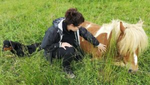 Femme caressant un poney dans l'herbe